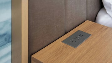 A wooden bedside table with a built-in power outlet.