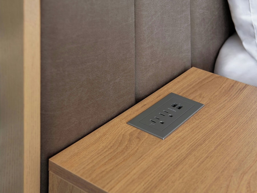A wooden bedside table with a built-in power outlet.