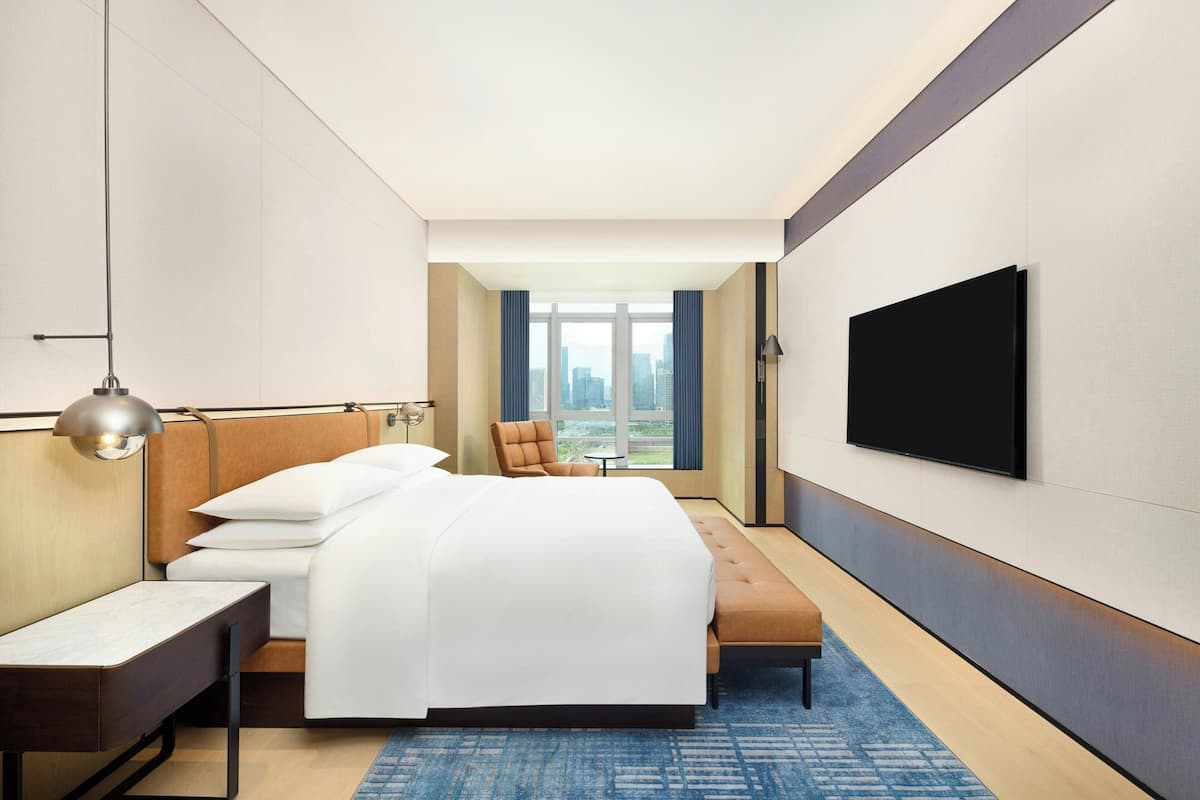 Un hotel moderno con una cama grande, un escritorio, un televisor y vistas a la ciudad.