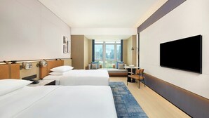 A hotel room with two beds, a TV, a desk, and a view of the city. - Four Points By Sheraton Nanning, Wuxiang (Nanning)
