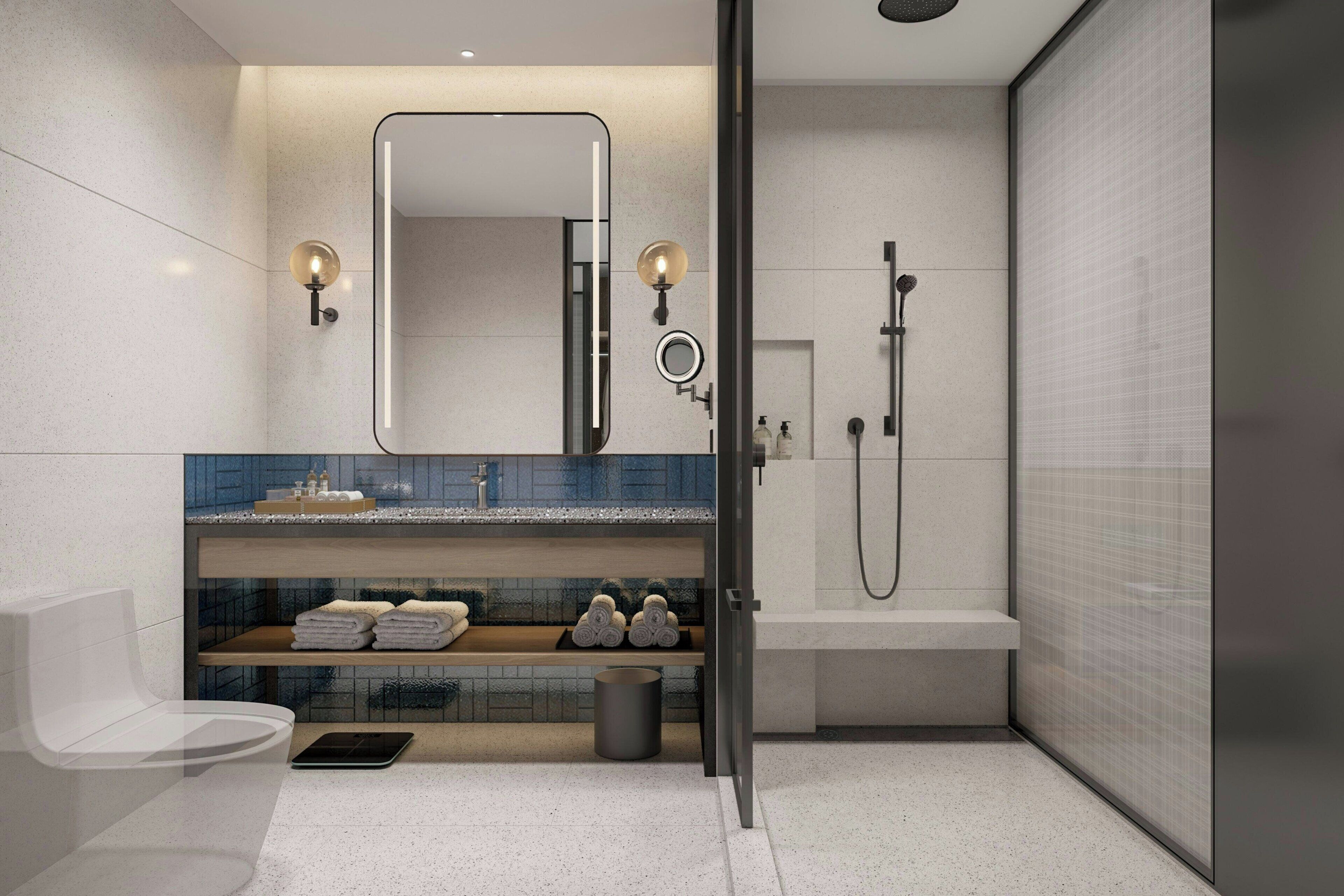 Un baño moderno con cabina de ducha de vidrio, lavamanos empotrado con espejo y perchero para toallas.