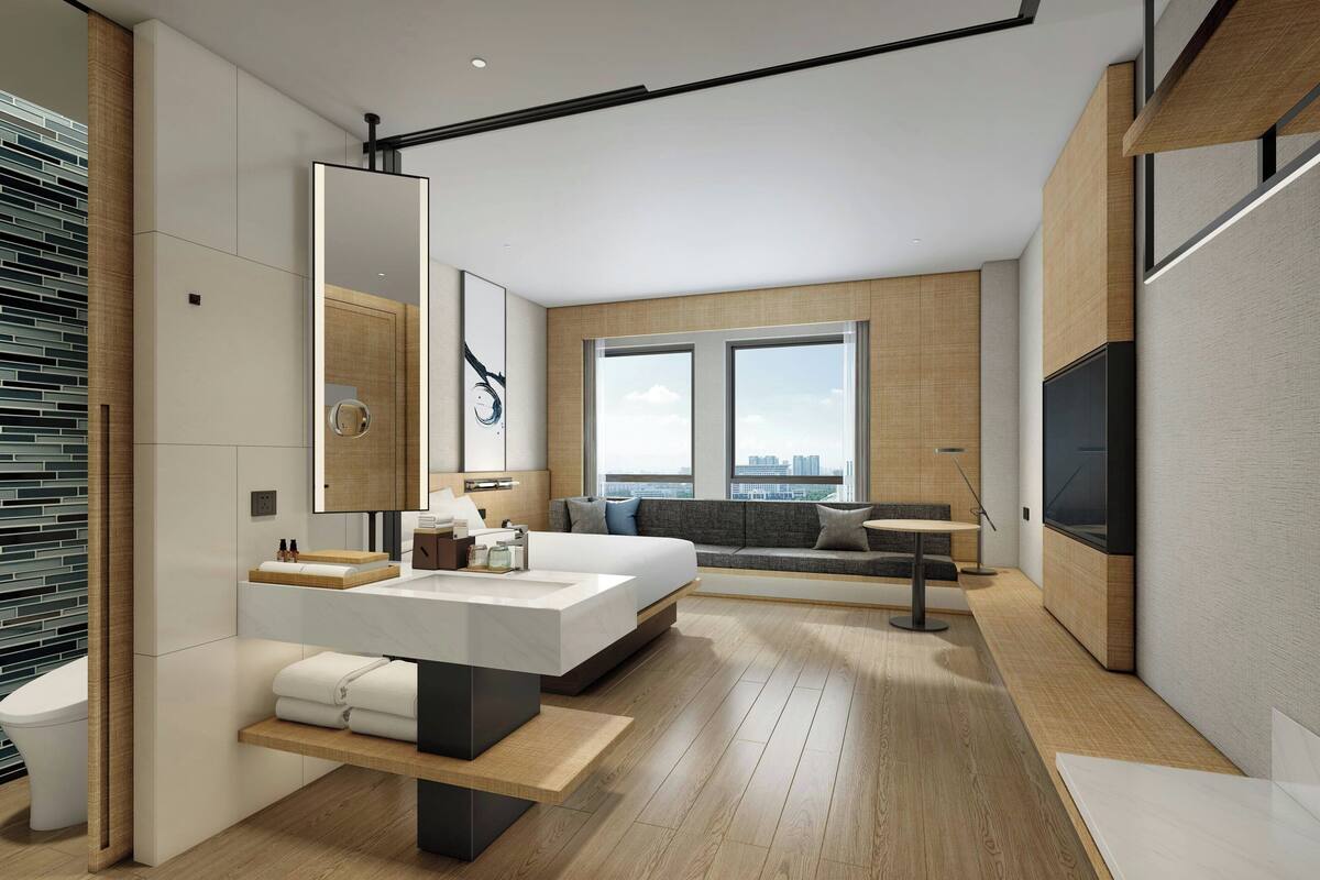 A modern hotel room with a large bed, a sitting area, a large window, and a TV.