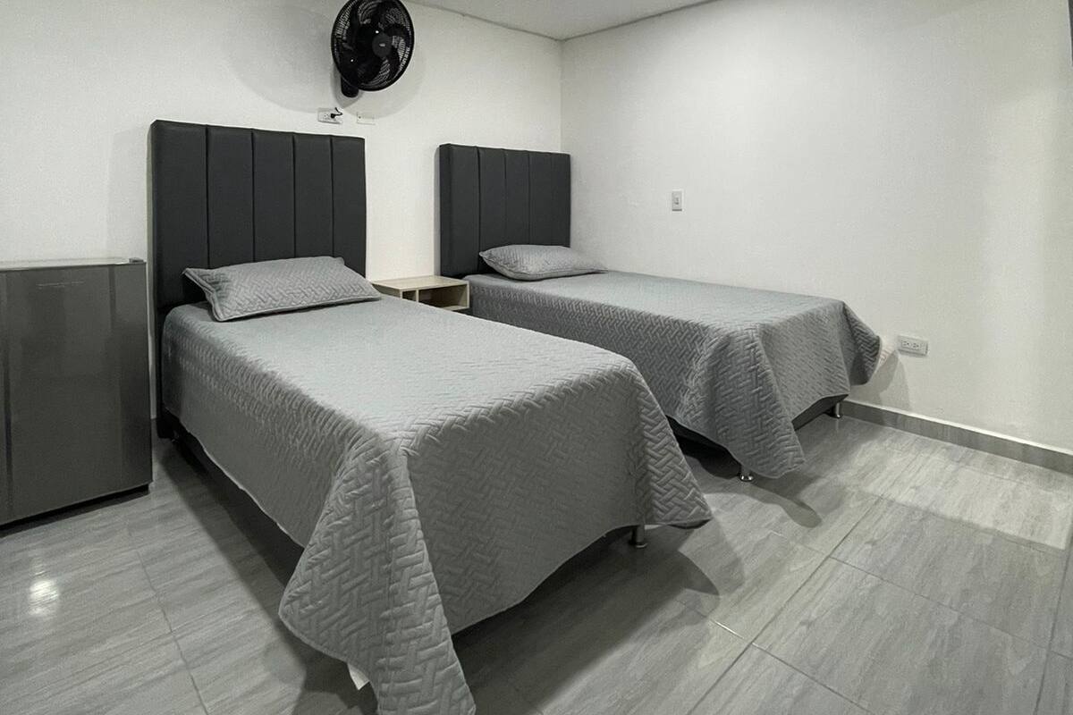 A modern bedroom with two beds, a ceiling fan, and a built-in wardrobe.
