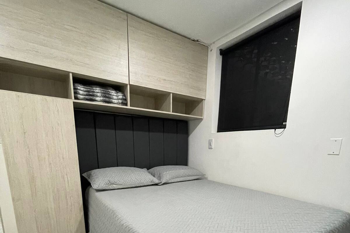 A bedroom with a bed, built-in storage, and a window.
