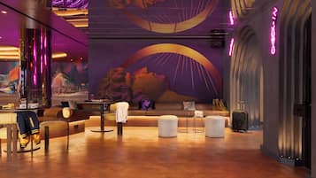 Un hall d’hôtel moderne, agrémenté d’une grande fresque murale, de coins salon et d’un comptoir d’enregistrement.