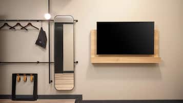 A modern room with a mounted TV, a mirror, and a clothing rack.