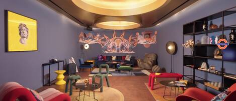 Een moderne woonkamer met een ronde plafondlamp, een muurschildering en een boekenkast.