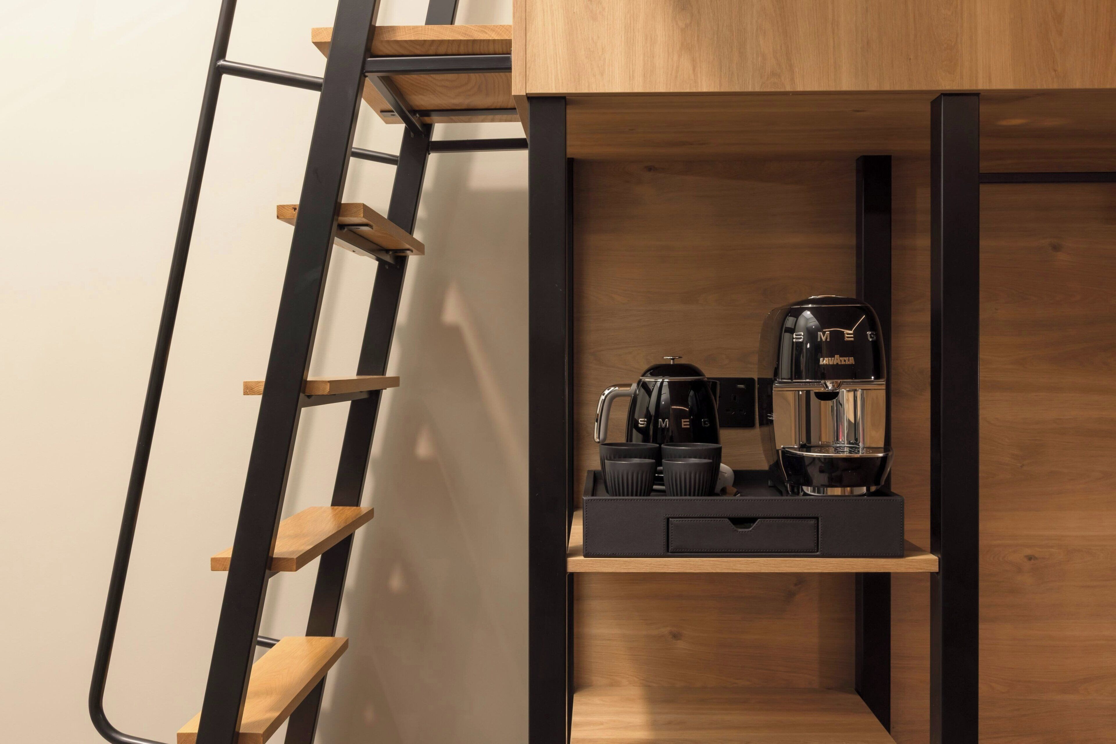 Eine moderne Küche mit integrierter Kaffeestation, Holzregalen und einer Treppe.