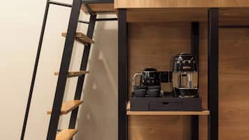Eine moderne Küche mit integrierter Kaffeestation, Holzregalen und einer Treppe.