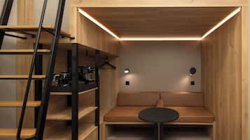 A compact room with a wooden bench, a small table, and a ladder leading to a loft area.