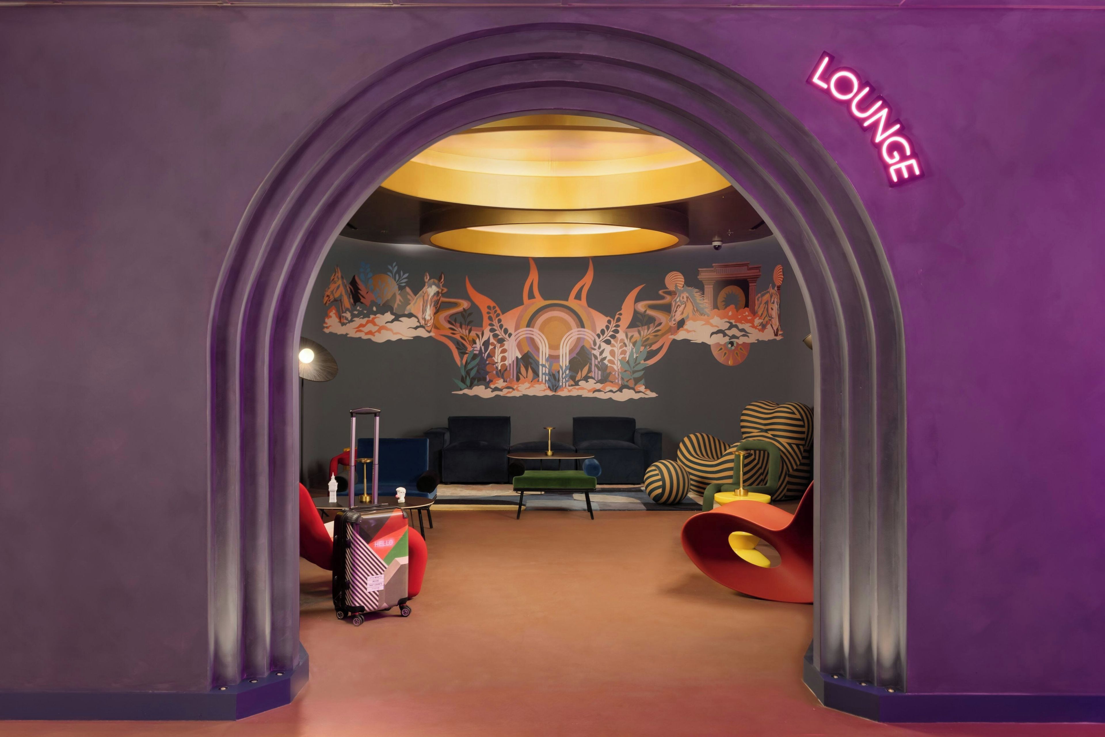 Un espace détente agrémenté d’une arche violette, d’une fresque murale et de mobilier contemporain.