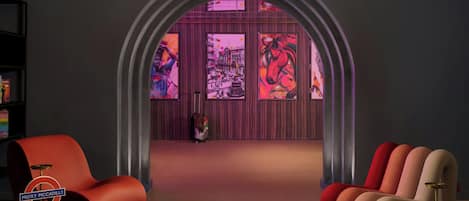 A modern interior with a central archway, a red armchair, a beige armchair, and a small table with a lamp.
