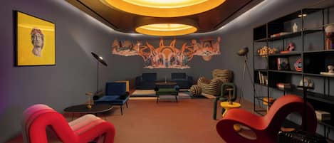 A modern living room with unique furniture, a large mural, and a ceiling light fixture.