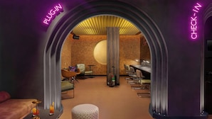 A hotel lobby with a check-in area, a reception desk, and a seating area with a large round table and chairs. - Moxy London Piccadilly Circus (London)