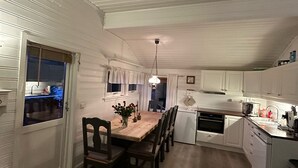 A compact kitchen with white cabinets, a wooden dining table, and a small refrigerator. - Maxi’s Cabin with Sauna and Jacuzzi (Troms)