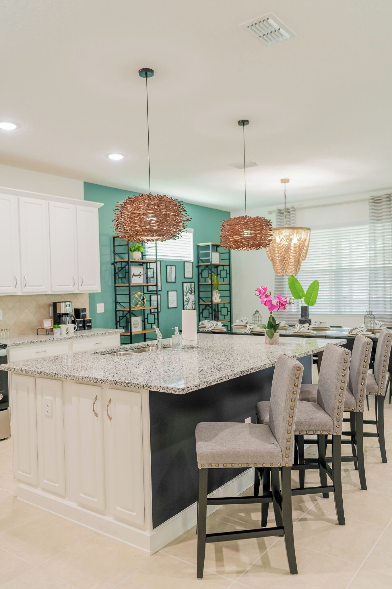 A modern kitchen with a central island, white cabinetry, and a teal accent wall.