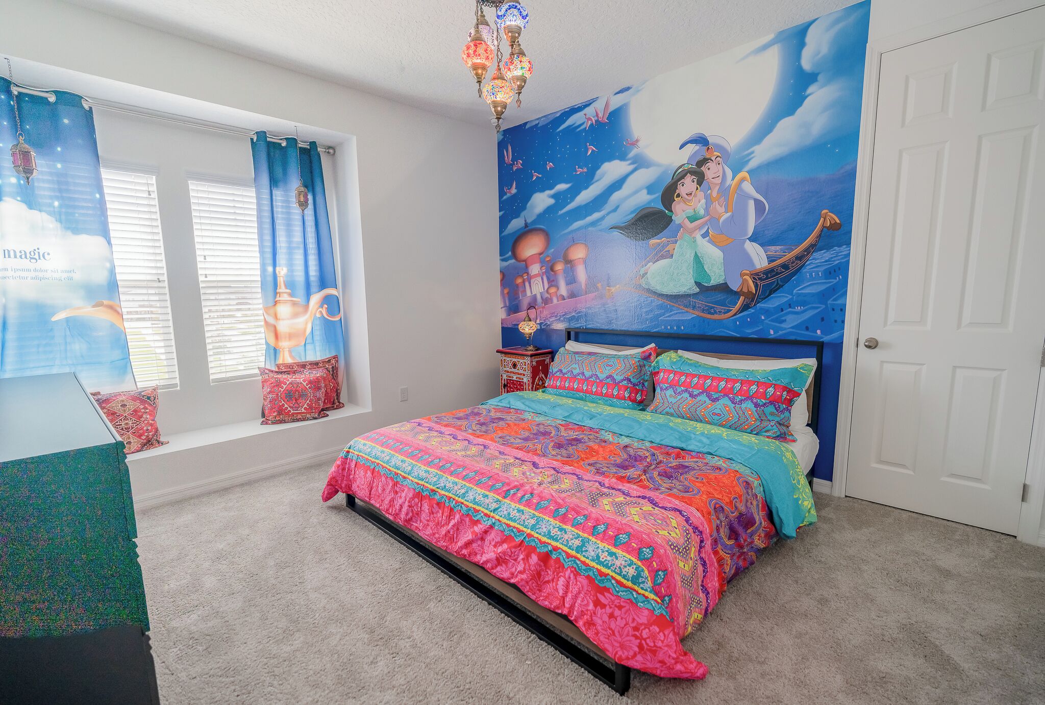 Un dormitorio con una cama grande, un mural de un personaje de cuento de hadas y una ventana con cortinas.