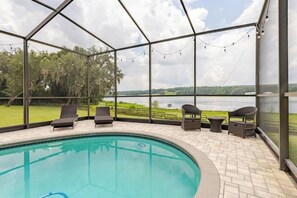 A covered outdoor swimming pool with lounge chairs and a view of a lake. - Water's Edge - a lakefront oasis. 10 peaceful, private acres w' stunning views. (Dade City)