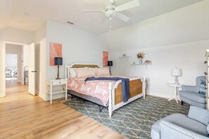 A bedroom with a bed, bedside tables, a ceiling fan, a chair, and a rug. - Water's Edge - a lakefront oasis. 10 peaceful, private acres w' stunning views. (Dade City)