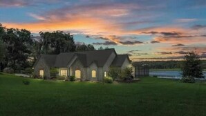 A house with a symmetrical facade, multiple chimneys, and a well-maintained lawn. - Water's Edge - a lakefront oasis. 10 peaceful, private acres w' stunning views. (Dade City)