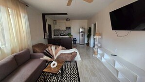Un salon moderne avec un canapé, une table basse et un téléviseur fixé au mur.