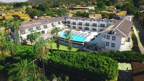 A hotel with a swimming pool, multiple floors, and a view of the surrounding hills. - Villa Santorini Boutique e Hotel  (Pirenópolis)