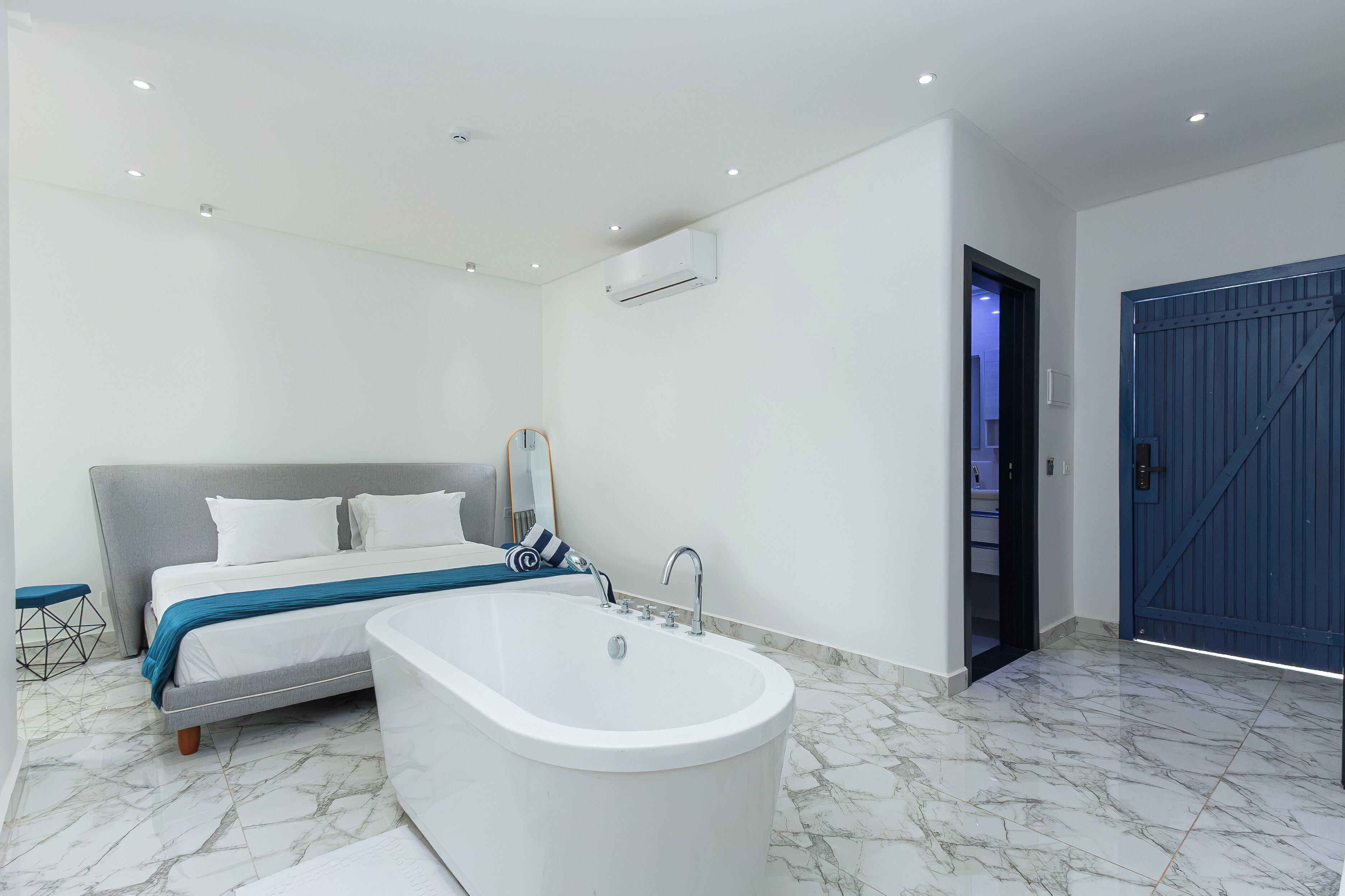Ein modernes Schlafzimmer mit einem großen Bett, einer Badewanne und einem Kleiderschrank.