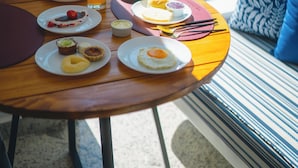 A breakfast table with various dishes, a cup of coffee, and a view of greenery through a window. - Villa Santorini Boutique e Hotel  (Pirenópolis)