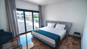 A modern hotel room with a large bed, a glass coffee table, a sofa, and a view of the outside. - Villa Santorini Boutique e Hotel  (Pirenópolis)