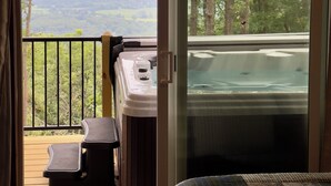 Un dormitorio con un ventanal grande, un jacuzzi y una terraza.