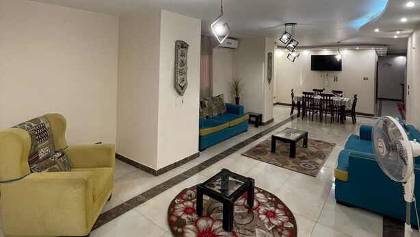 A modern living room with a sofa, armchairs, a coffee table, and a dining area with a TV. - wake up to the pyramids (Giza)