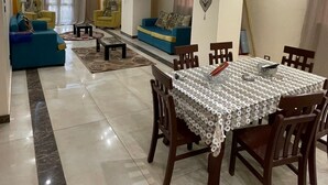 A spacious living area with a dining table, sofas, and a TV. - wake up to the pyramids (Giza)
