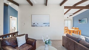 A living room with a view of the ocean, a dining area, and a staircase. - Pacific Chillz in Ulladulla (Ulladulla)
