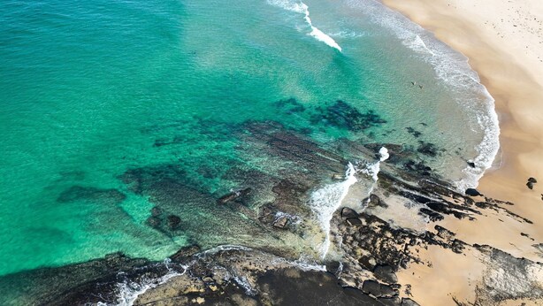 A coastal landscape with clear turquoise waters, sandy beach, and rocky outcrops. - Pacific Chillz in Ulladulla (Ulladulla)
