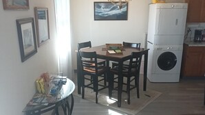 A compact living space with a dining area, a sofa, a washing machine, and a chandelier.