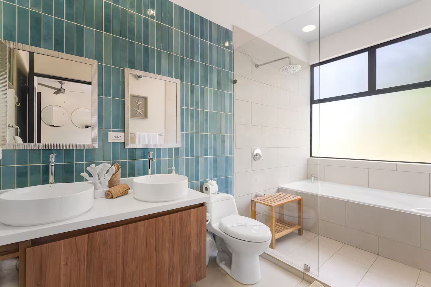 A modern bathroom with two sinks, a toilet, a shower, and a bathtub.