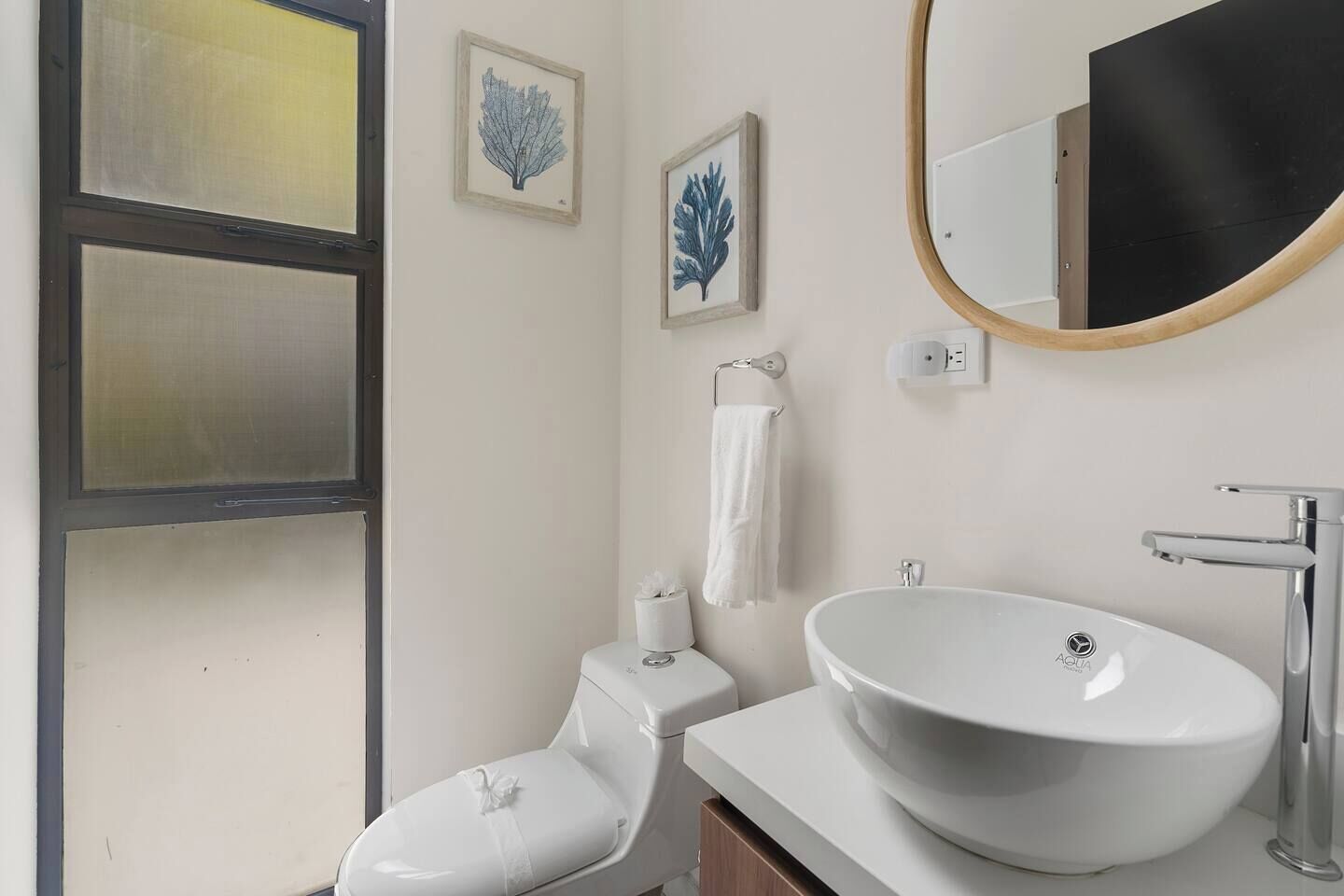 A bathroom with a white toilet, a white sink, and a large mirror.