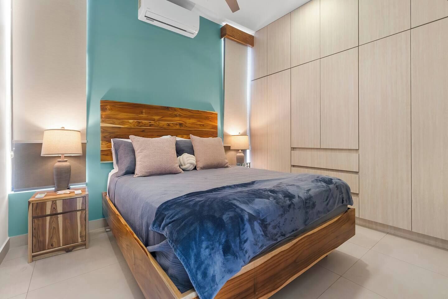 Ein modernes Schlafzimmer mit einem Holz-Kopfteil, einem Bett mit blauer Decke und einem Nachttisch mit einer Lampe.