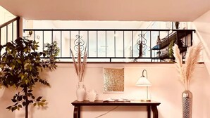Een gezellige zithoek met een houten console, een witte lamp, decoratieve vazen en een grote potplant.