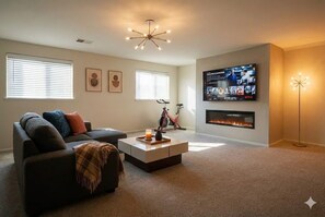 Una sala de estar moderna con un sofá, una mesa de centro, una chimenea y un televisor montado en la pared.