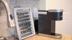 Eine Kaffeemaschine von Keurig steht auf einer Granit-Arbeitsplatte neben einem gerahmten Motivationsspruch.