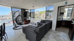 A modern living room with a gray sofa, a hanging chair, and a small table. - Apartment with ocean and golf course views (Acapulco de Juárez)