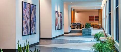 A spacious hallway with modern decor, including abstract art and potted plants.