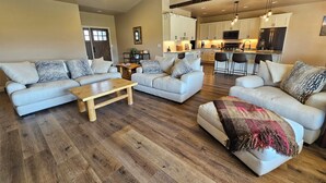 A spacious living room with two sofas, a coffee table, and a kitchen in the background. - Experience Desert Gemini Ranch and the magic of the Colorado high desert (Fruita)