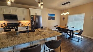 A modern kitchen with granite countertops, stainless steel appliances, and pendant lighting. - Experience Desert Gemini Ranch and the magic of the Colorado high desert (Fruita)