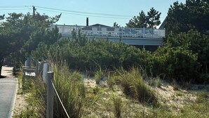 Una casa de playa con terraza blanca y porche cubierto.