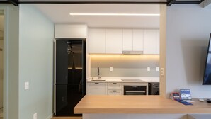 A modern kitchen with white cabinetry, a stainless steel refrigerator, and a wooden countertop. - Studio Just a few Steps From the Beach - Kpl0806 (Sao Jose)