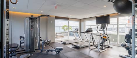 A gym with treadmills, weight machines, and a rowing machine.