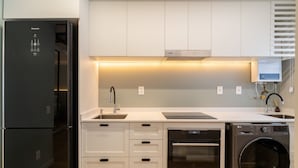 A modern kitchen with a built-in dishwasher, oven, and refrigerator. - Studio Just a few Steps From the Beach - Kpl0806 (Sao Jose)