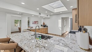 A modern kitchen with a large island, a skylight, and a view of the outdoors. - Del Rio Luxe | Design-Driven 3BR Home with Pools & Tennis (Tucson)